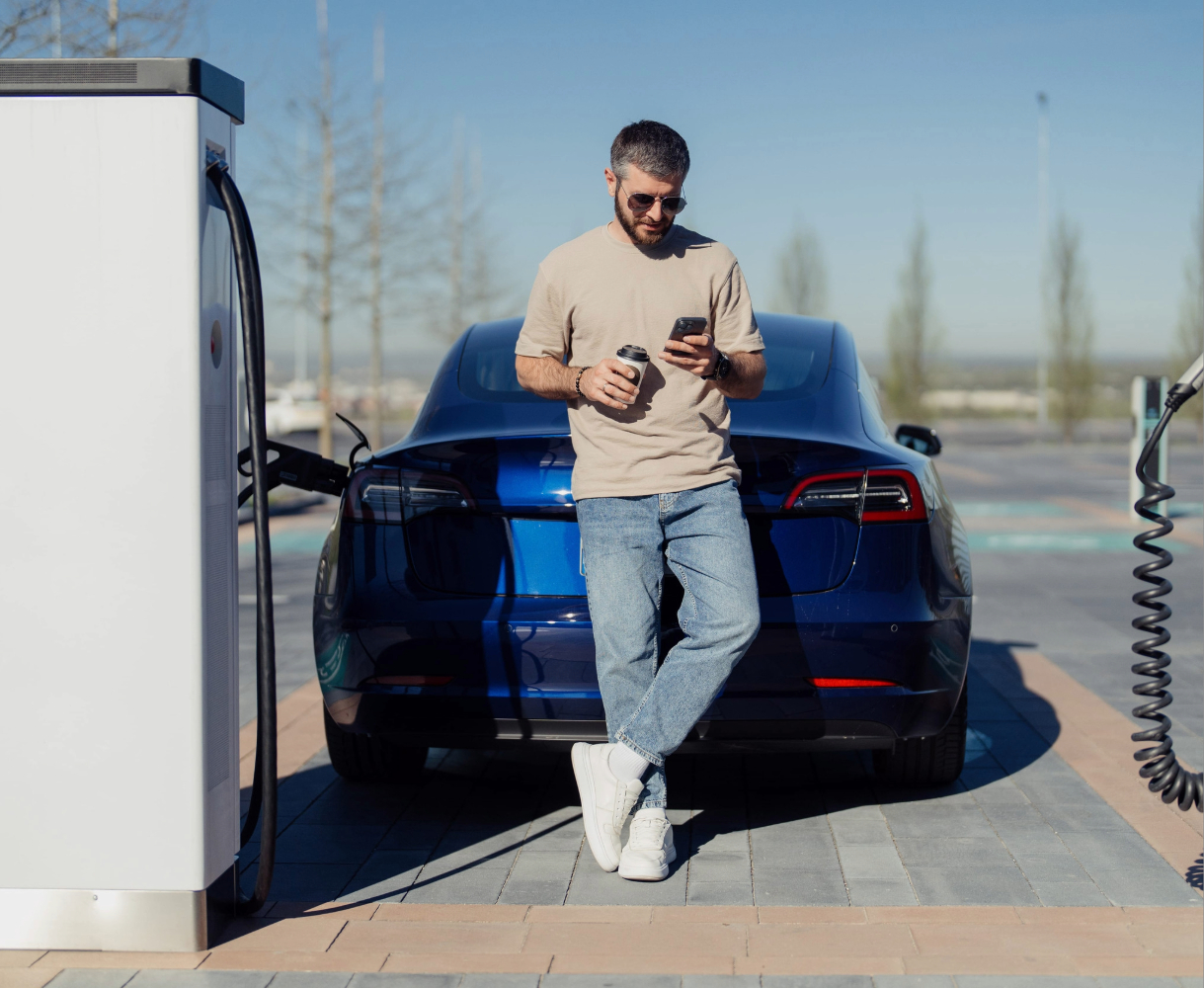 Hombre esperando que su vehículo eléctrico cargue