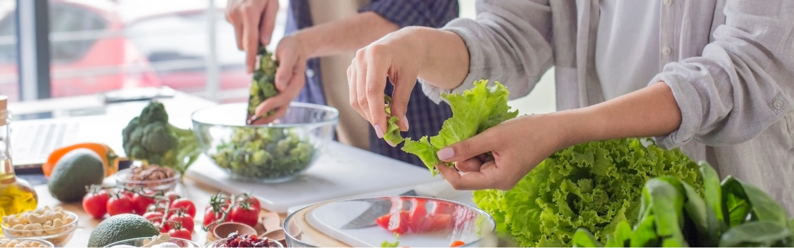 pareja preparando ensalada saludable en casa como parte de una alimentación saludable