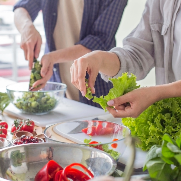 pareja preparando ensalada saludable en casa como parte de una alimentación saludable