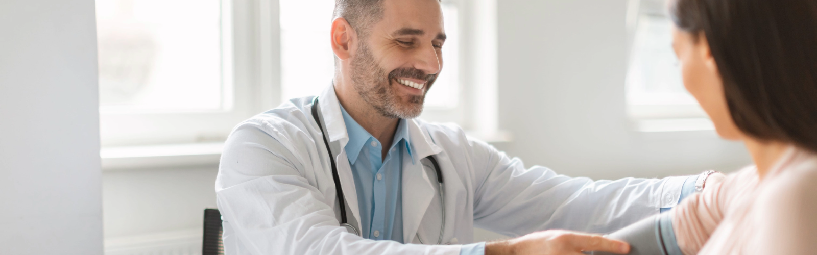Doctor en chequeo médico midiendo la presión arterial a una paciente 