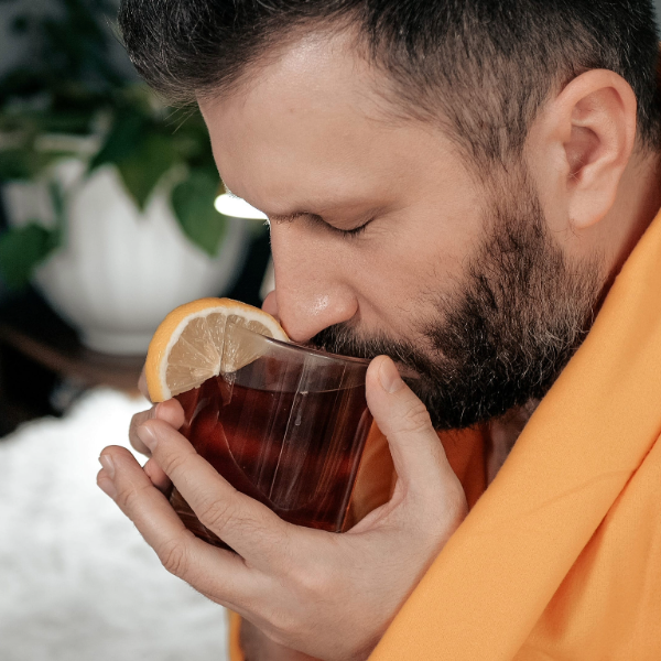 hombre tomando té con limón como uno de los remedios caseros para la tos con flema y el alivio de la congestión
