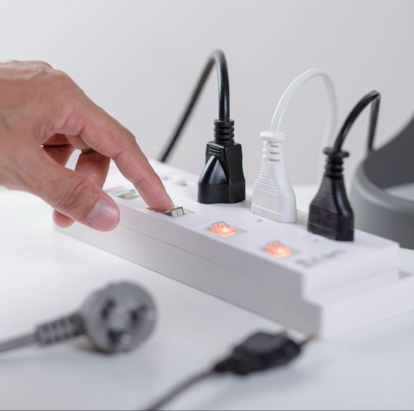 mano apagando una multitoma eléctrica para mejorar la seguridad eléctrica en el hogar