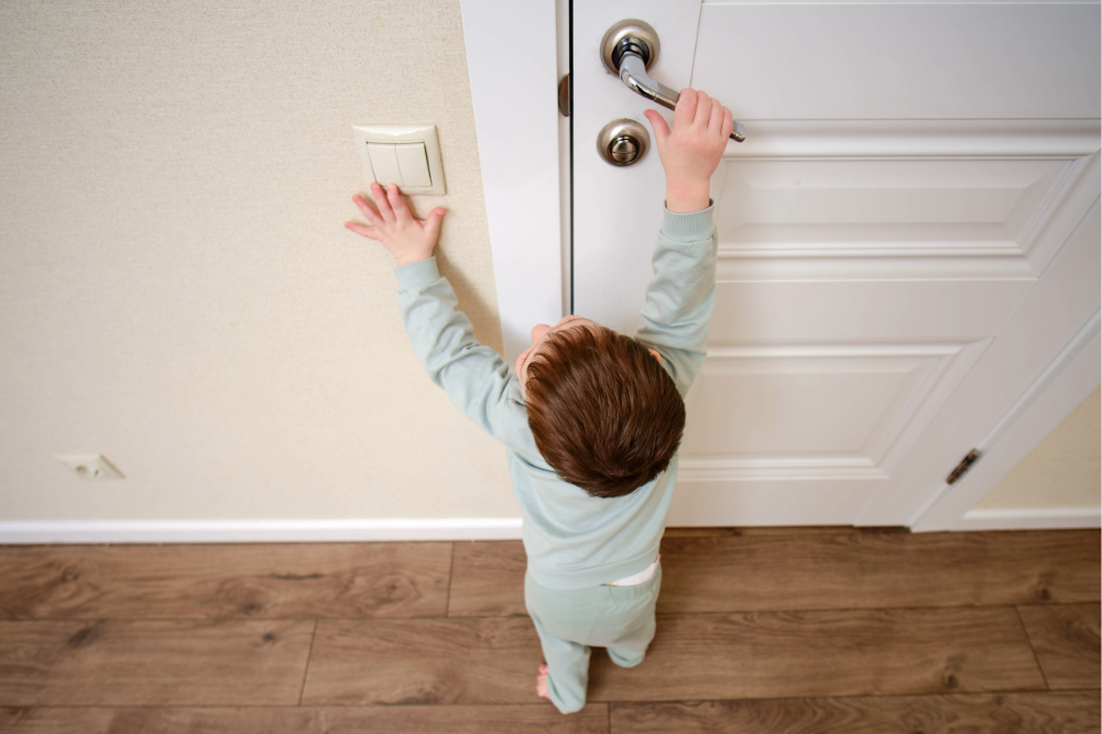 niño intentando alcanzar la manija de una puerta, situación que refleja riesgos comunes en el hogar