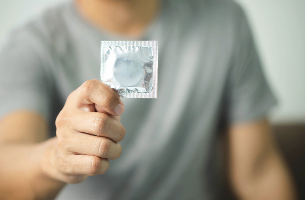 hombre sosteniendo un sobre de condones como parte de la prevención de las its