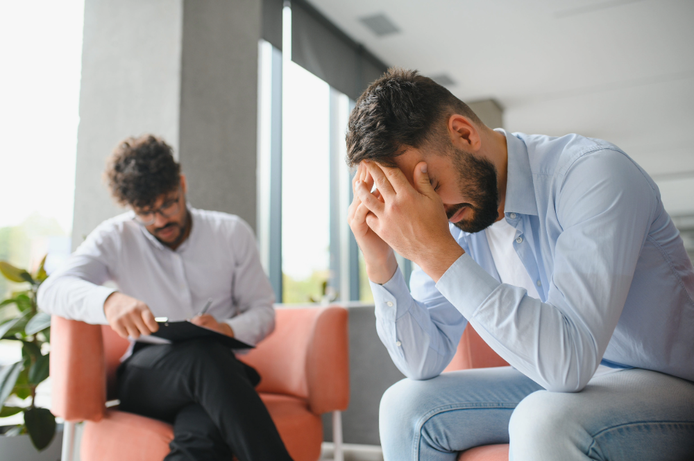 psicólogo tomando notas mientras escucha a un paciente masculino en sesión de terapia