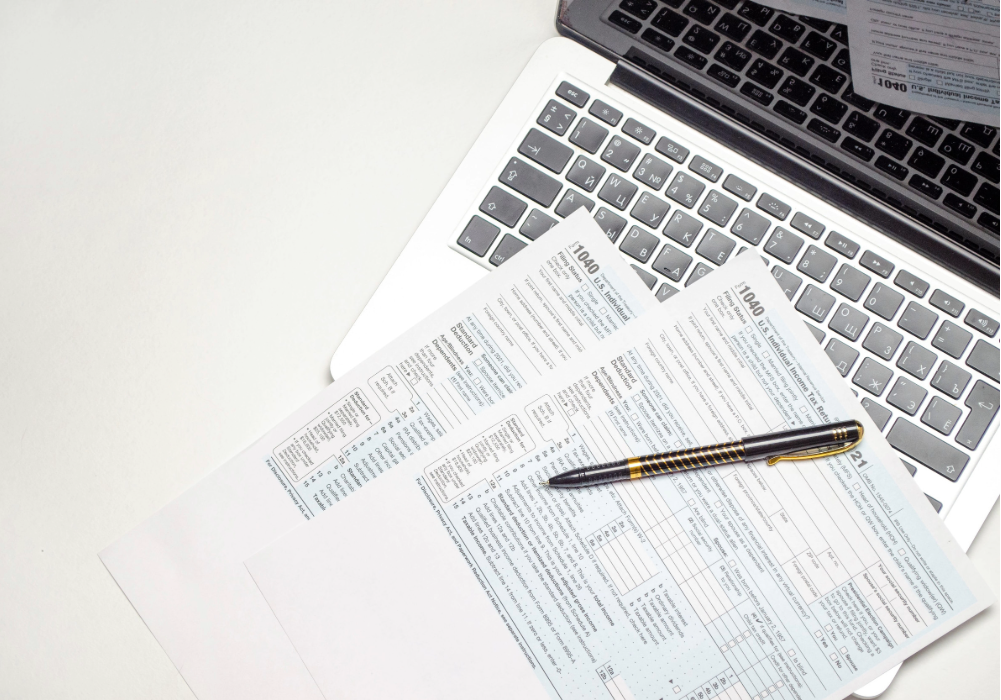 escritorio con formularios fiscales y laptop para gestión de impuestos