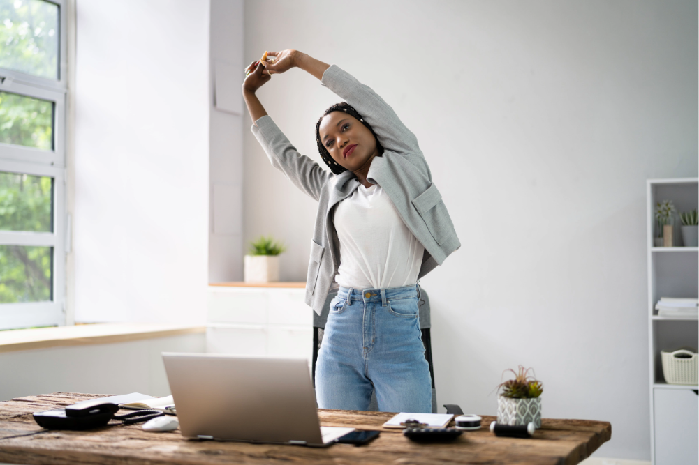 mujer realizando pausas activas en su escritorio de oficina