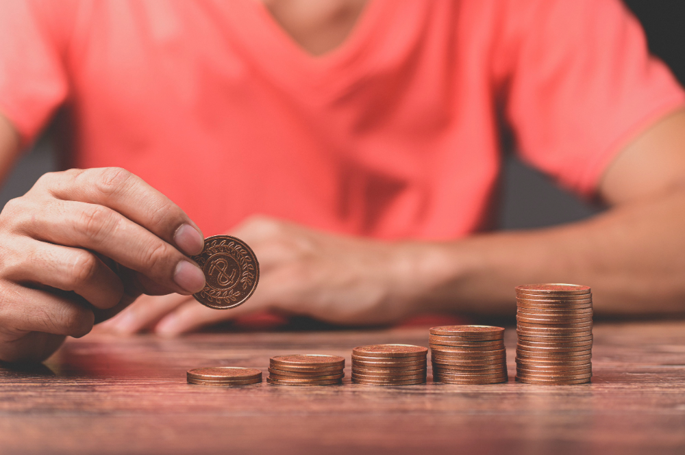planta en crecimiento sobre una pila de monedas que representa el ahorro
